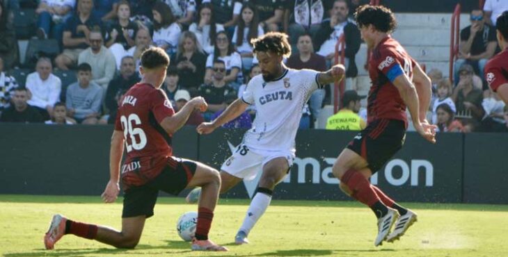 Konrad de la Fuente intenta salvar la presión de dos rivales.