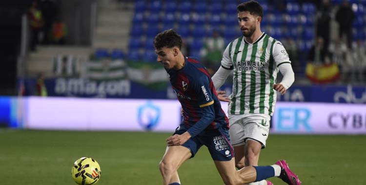 Jacobo trata de ganar el balón ante un zaguero del Huesca.